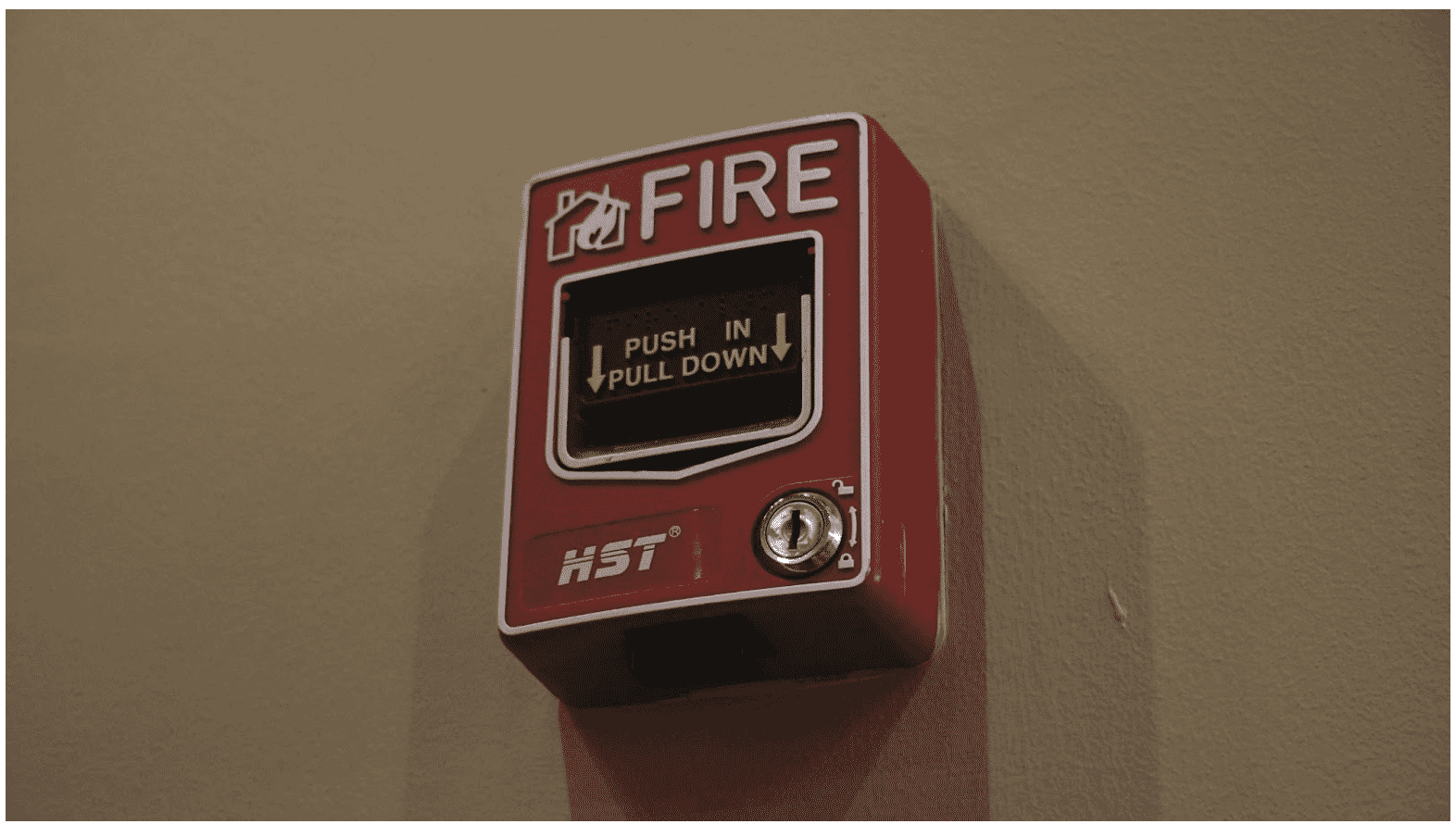 Red fire alarm pull station mounted on a wall, highlighting the importance of low-voltage fire cables in ensuring reliable fire detection and alarm systems