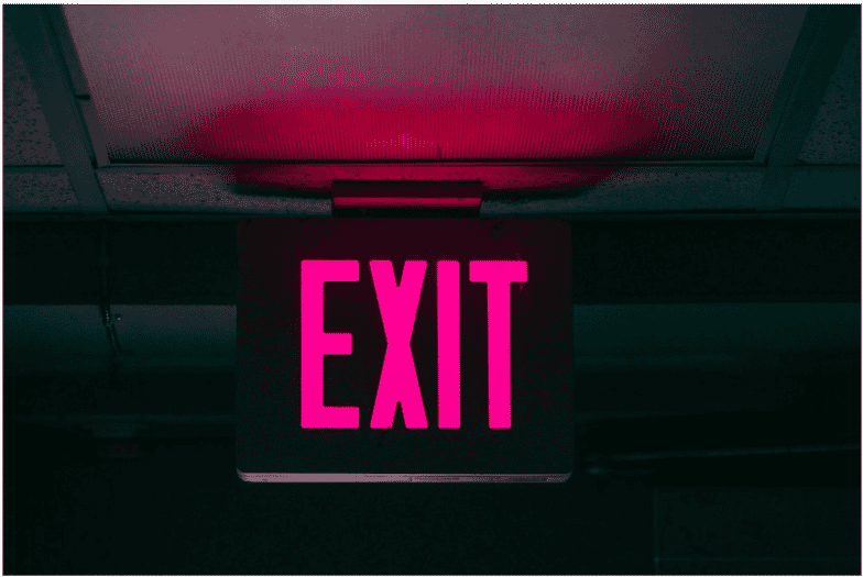 Illuminated exit sign glowing red in an indoor space, emphasizing the necessity of fire-rated plenum cable to ensure safe and reliable emergency lighting