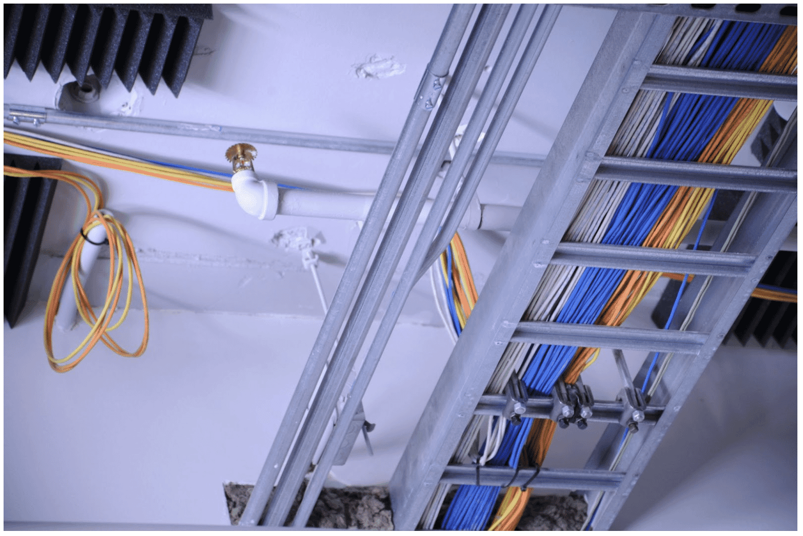A close-up view of fire-rated cables organized in a metal cable tray along a ceiling, demonstrating the durability and protection of 2-hour fire-rated cable in high-risk environments
