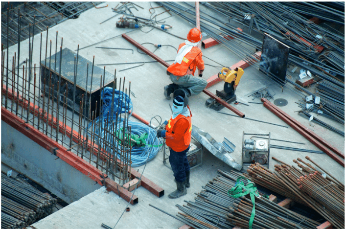 Construction workers handling rebar and electrical materials on a job site, with heavy-duty underground cables coiled and ready for reliable power distribution